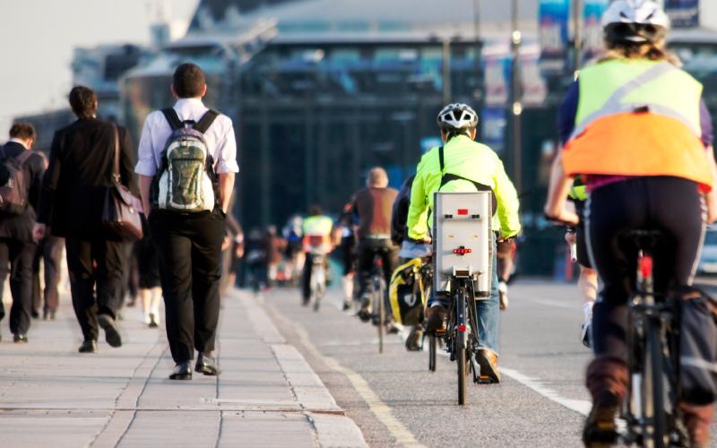 Commuters walking and cycling along a busy street