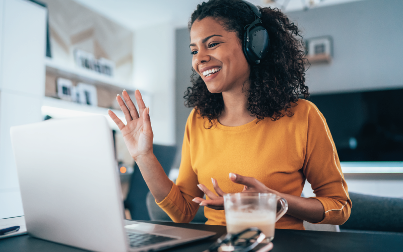 Photograph of smiling young woman wearing a headset sat at a laptop