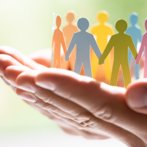 Dwylo’n dal yn ofalus grŵp o ffigurau papur lliwgar wedi’u torri allan, yn sefyll mewn cylch.